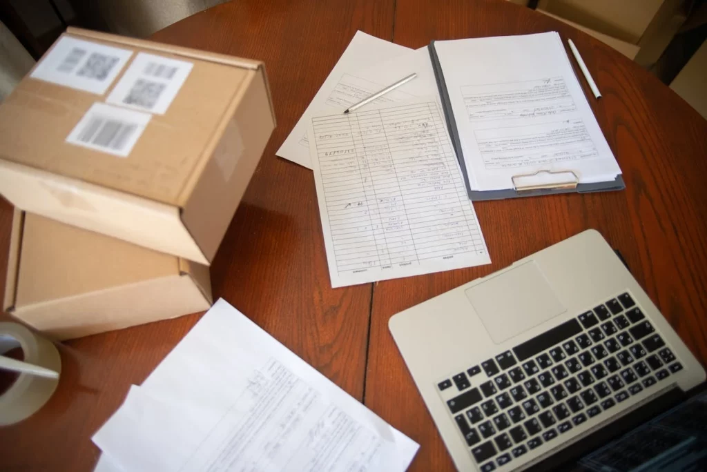 Organizing Operational Inefficiencies looking at paperwork , laptop and a bunch of cardboard boxes