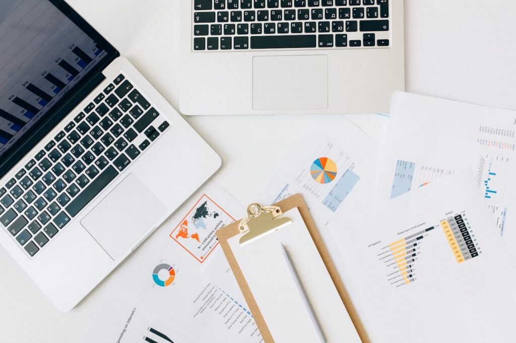 Overhead view of laptops, analytics reports, and performance charts used for supply chain data analysis and business planning. The image represents inventory forecasting, procurement analytics, and digital supply chain management.