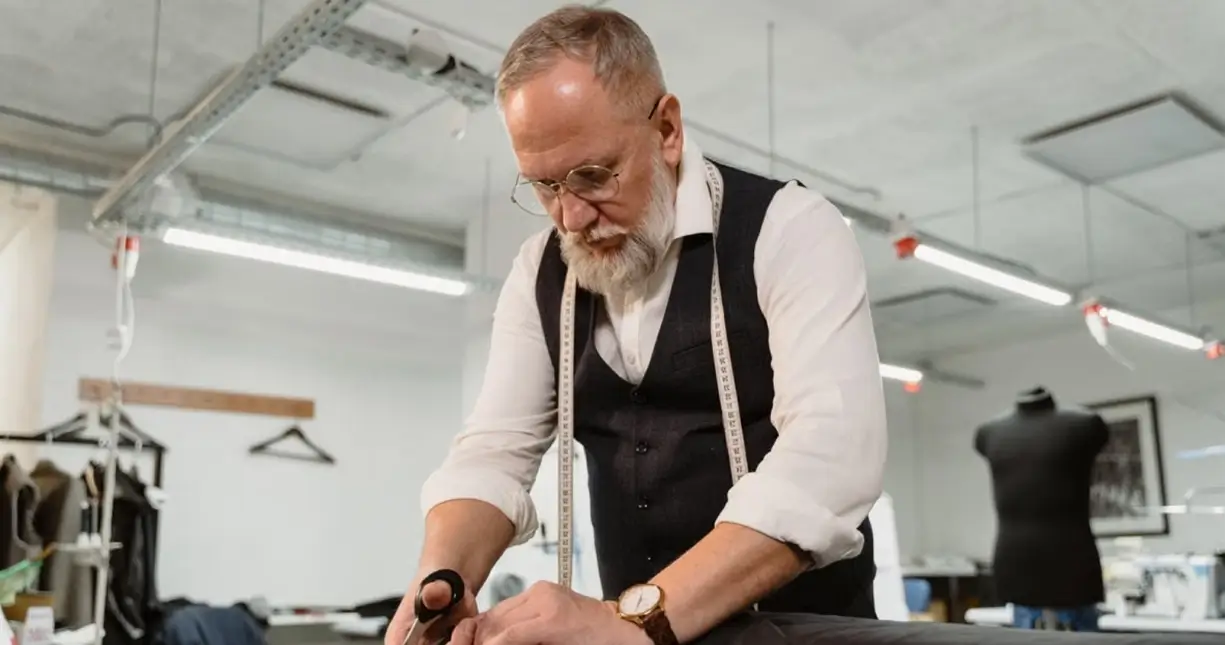 Yushkova Designs A tailor cutting fabric on a cutting table