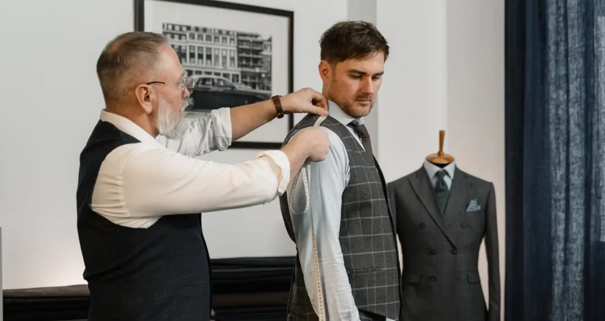 Yushkova Designs A tailor measuring a client with a tape measure